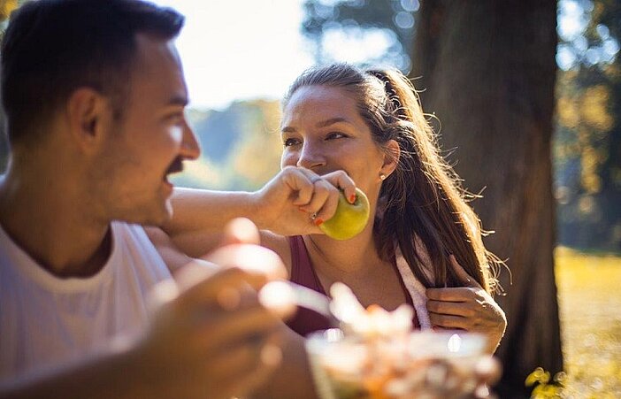 Junges Paar isst gesundes Picknick mit niedrigem glykämischen Index im Park