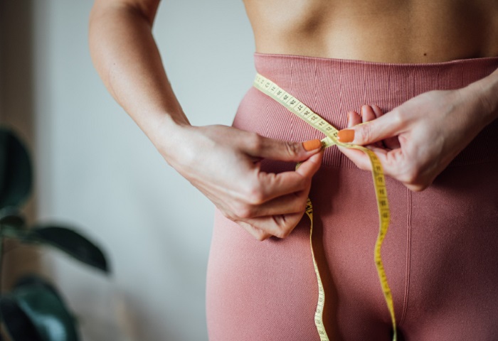 junge Frau mit gesundem BMI misst ihren Bauchumfang