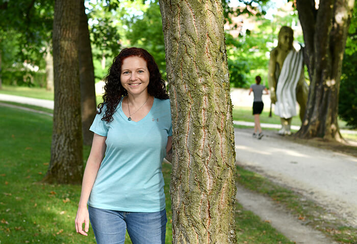 Cindy steht zwischen den Bäumen im Park und berichtet über ihre Almased Erfolge