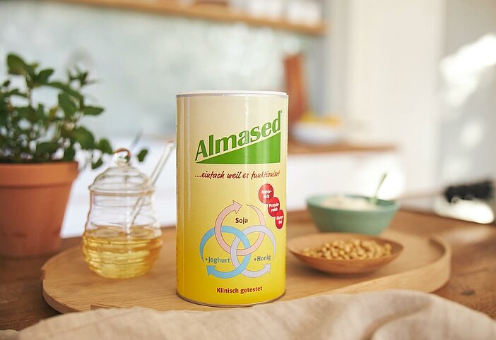 Almased Original 500g Dose gemeinsam mit Honig, Soja und Joghurt auf einem Tisch, Almased bietet einfach mehr