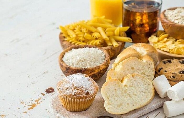 Weißbrot, Cola, Muffin und andere Süßigkeiten mit hohem glykämischen Index auf einem Brett drapiert