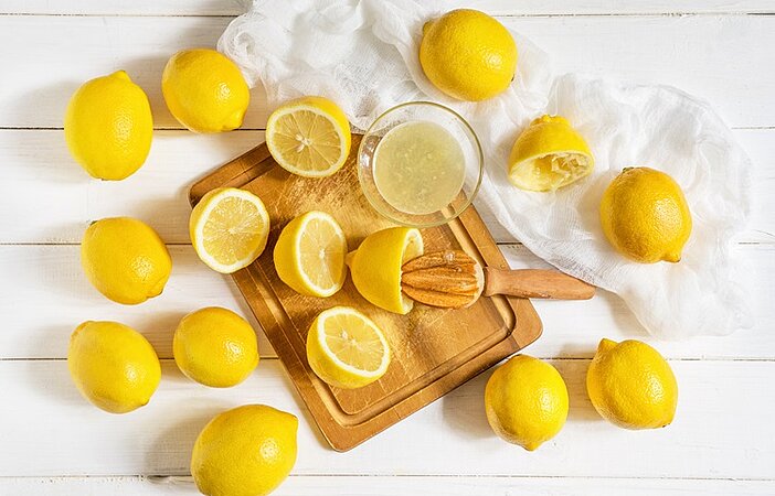Zitronen aufgeschnitten auf Holzbrett als Stoffwechsel Booster