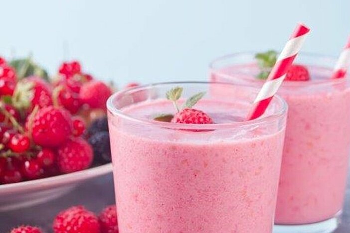 Rosa Abnehmshake mit Himbeeren in zwei Gläsern mit Strohhalm