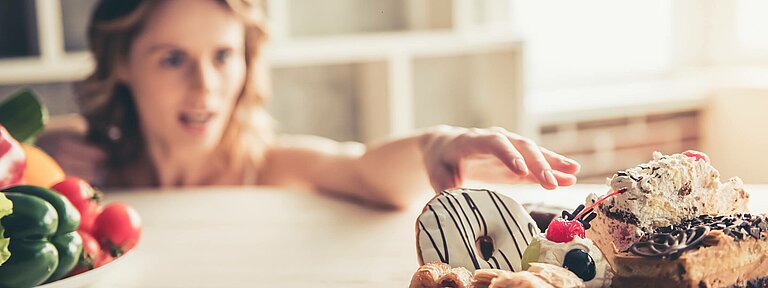 Frau-mit-Heisshunger-greift-nach-Kuchen