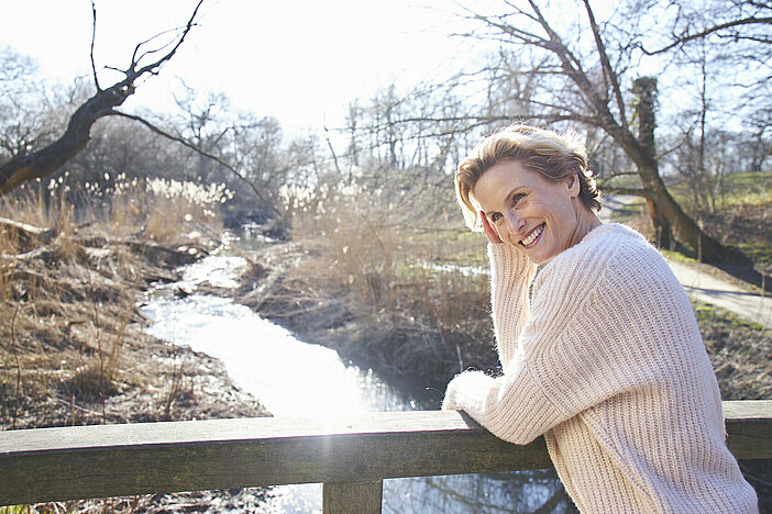 Frau im menopausalen Alter auf einer Brücke