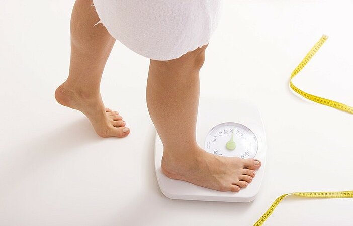 Frau-steigt-auf-Waage-Zunahme-durch-Heißhunger