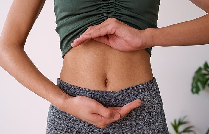 Frau-haelt-Haende-ueber-Bauch-um-Verdauung-und-Stoffwechsel-darzustellen