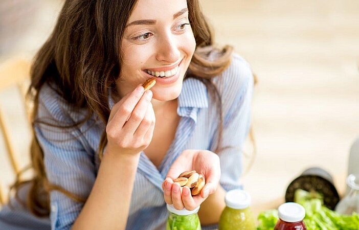 Junge Frau isst Nüsse, um sich an die glykämische Index Diät zu halten