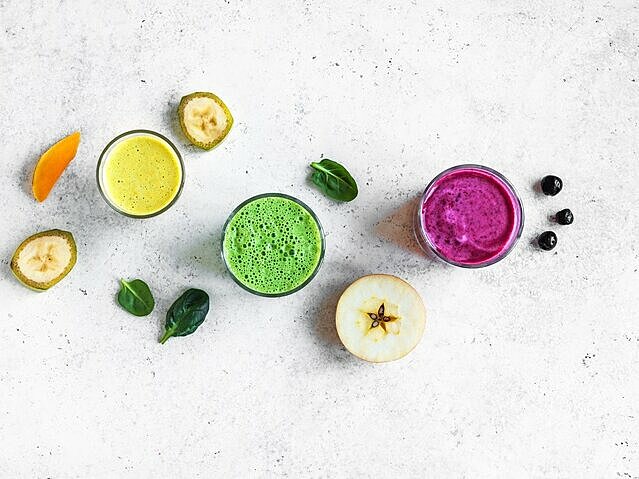 3 bunte Smoothies im Glas mit gesunden Zutaten drumherum